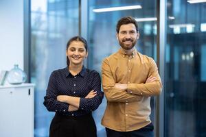 Smiling business professionals stand together with arms crossed in a bright, modern office setting, ready for success. photo