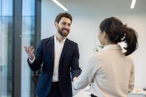 A business professional is shaking hands with a colleague in a modern office setting. This portrays a collaborative work environment. photo