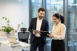 A diverse team of professionals collaborates in a modern office environment, reviewing documents and using a tablet together, creating a focused work atmosphere. photo
