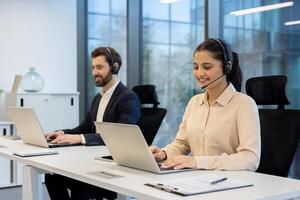 Smiling customer service representatives working in a modern office, using laptops and headsets, assisting clients professionally. photo