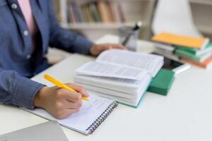 A person studies and takes notes in a book-filled setting, emphasizing education and learning environment. photo