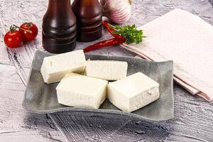 A plate of tofu cubes on a table with a bottle of ketchup and a bottle of vinegar photo