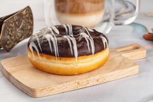 A donut sitting on a cutting board next to a cup of coffee photo