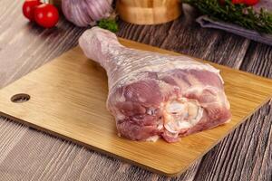A raw pork leg on a cutting board with vegetables photo