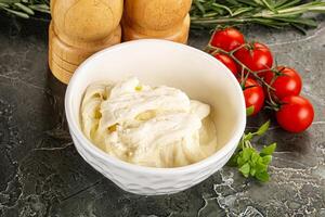A bowl of cream cheese next to a pepper and a tomato photo