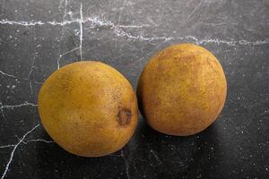 Two ripe kiwis on a black surface photo