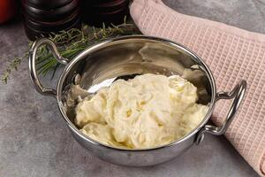 A metal bowl filled with butter next to a towel photo