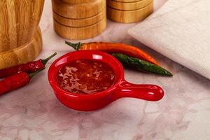 A red bowl with chili sauce and a knife photo
