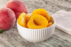 A bowl of peaches sitting on a table next to a bowl of peaches photo