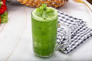 A green drink with a pineapple on top photo