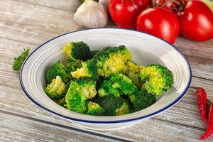 A bowl of broccoli with tomatoes and peppers on a table photo