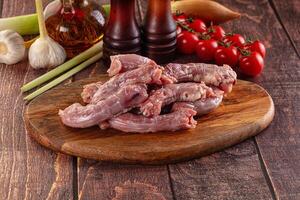 Raw chicken on a cutting board with garlic, tomatoes and other ingredients photo