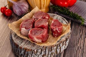 Raw meat on a wooden table with tomatoes and garlic photo