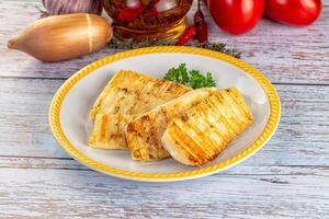 Grilled fish fillet on a white plate with tomatoes and herbs photo