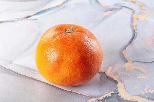 A close up of an orange on a marble surface photo