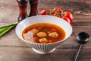 A bowl of soup with meatballs and tomatoes photo