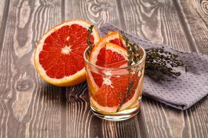 A glass of orange juice and a grapefruit on a wooden table photo