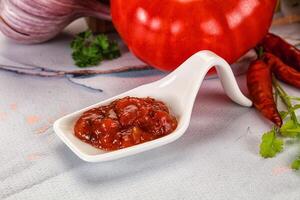 A white scoop with a tomato and some other ingredients photo