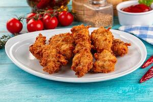 Fried chicken wings on a white plate with sauce and tomatoes photo
