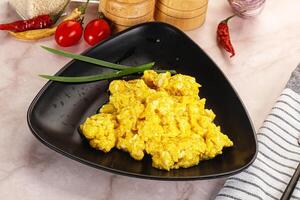 A black bowl with scrambled eggs on it photo