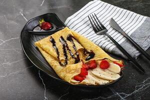 A plate with a crepe with strawberries and bananas on it photo