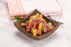 A wooden bowl with a bowl of gummy worms photo