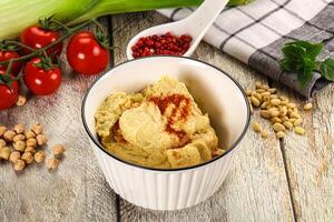 A bowl of hummus with spices and vegetables photo