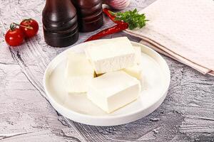 A white plate with cubes of cheese and a bottle of wine photo