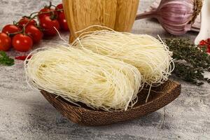 A bowl of noodles, garlic, and tomatoes on a table photo