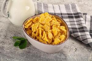 Corn flakes in a bowl and a glass of milk on a rustic table photo