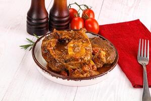 A plate of meat with tomatoes and a fork photo