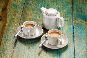 A table with two cups of coffee and a teapot photo