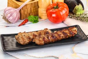 Two pieces of meat on a black plate with vegetables photo