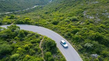 Aerial view of winding mountain road with car navigating through lush greenery photo