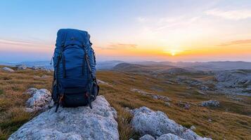 backpack rests boulder, overlooking breathtaking landscape sunrise. scene evokes sense photo