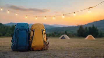 Camping scene with two backpacks and string lights at sunset, creating warm atmosphere photo