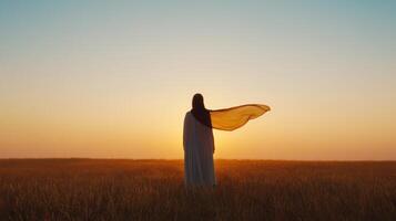 figure in flowing cloak stands in golden field at sunset, evoking sense of peace and wonder photo