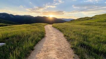 serene hiking trail winds through lush green grass, leading towards stunning sunset over photo