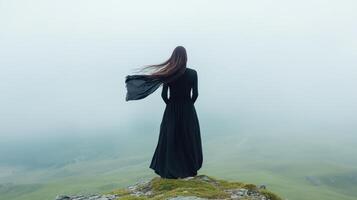 Dramatic moment on rocky edge with flowing scarf in wind photo