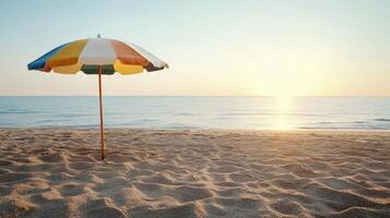 An umbrella is sitting on the beach at sunset photo
