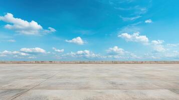Vast empty landscape with clear blue sky and scattered clouds above concrete surface photo
