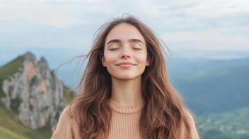 Gazing peacefully with closed eyes, young woman enjoys gentle breeze on mountain photo