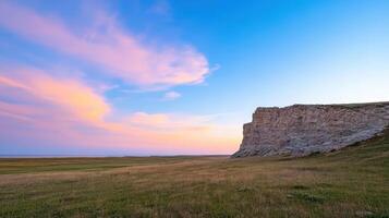 A sunset over a cliff with grass and a blue sky photo