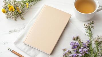 A notebook, pen, and flowers on a white table photo