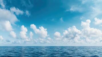 Vast ocean under clear blue sky with fluffy clouds creating serene atmosphere photo