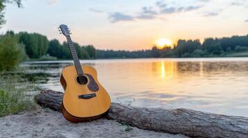 Guitar resting on log by serene lake at sunset creates peaceful ambiance photo