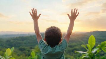 Child with hands raised toward sky, surrounded by lush greenery and beautiful sunset photo