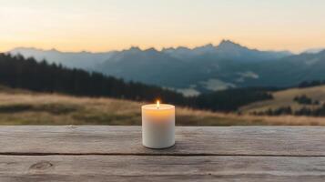 Candle glowing softly on wooden table with stunning mountain view at sunset photo