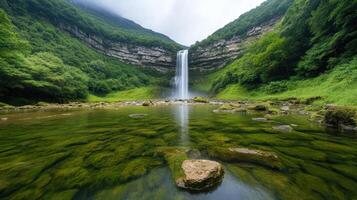 Majestic waterfall cascading into serene pool, surrounded by lush greenery and rocky terrain photo