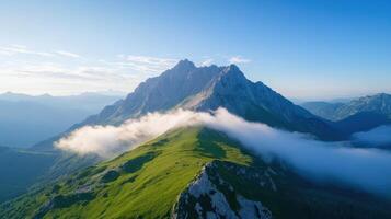 Majestic mountain peak surrounded by lush greenery and soft clouds, showcasing nature beauty photo